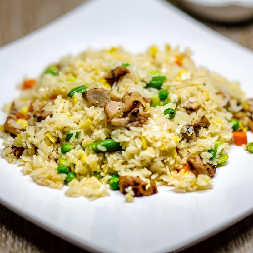 A close-up of Jackpot Teriyaki's chicken fried rice with peas, carrots, and egg on a white plate.