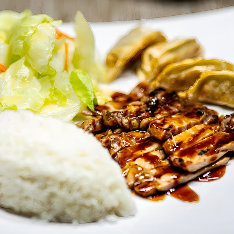 Jackpot Teriyaki chicken teriyaki plate with rice, salad, and gyoza on a white plate.
