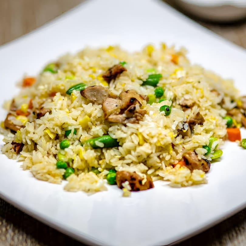 Close-up of Jackpot Teriyaki's chicken fried rice with peas, carrots, and egg on a white plate.